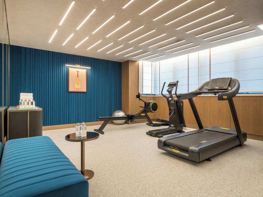 A fitness room with exercise equipment, a blue sofa, and a wall-mounted picture.