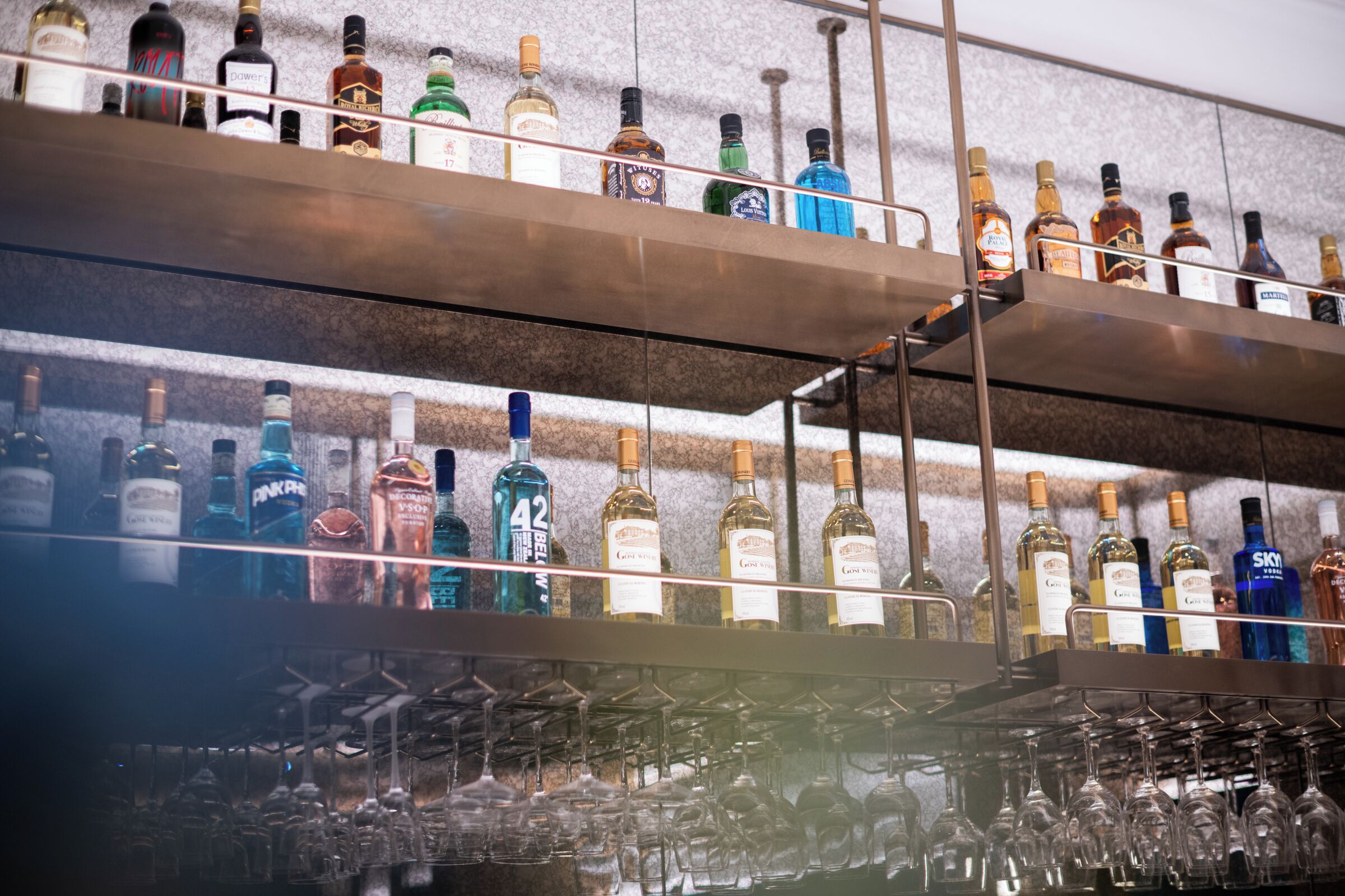 Un bar con varias estanterías llenas de botellas de licores y copas de vino.