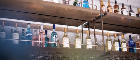 A bar with multiple shelves of liquor bottles and wine glasses.