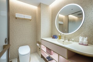 A modern bathroom with a toilet, sink, mirror, and shelves.