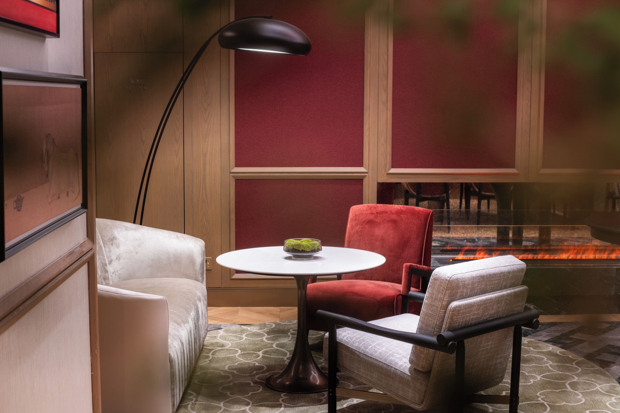 Een knus ingerichte kamer met een open haard, een ronde tafel met een schaal en twee stoelen.