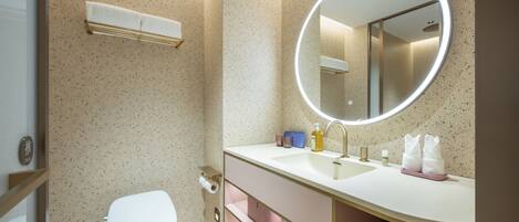 Un bagno moderno con un WC bianco, uno specchio rotondo e un mobile lavabo.