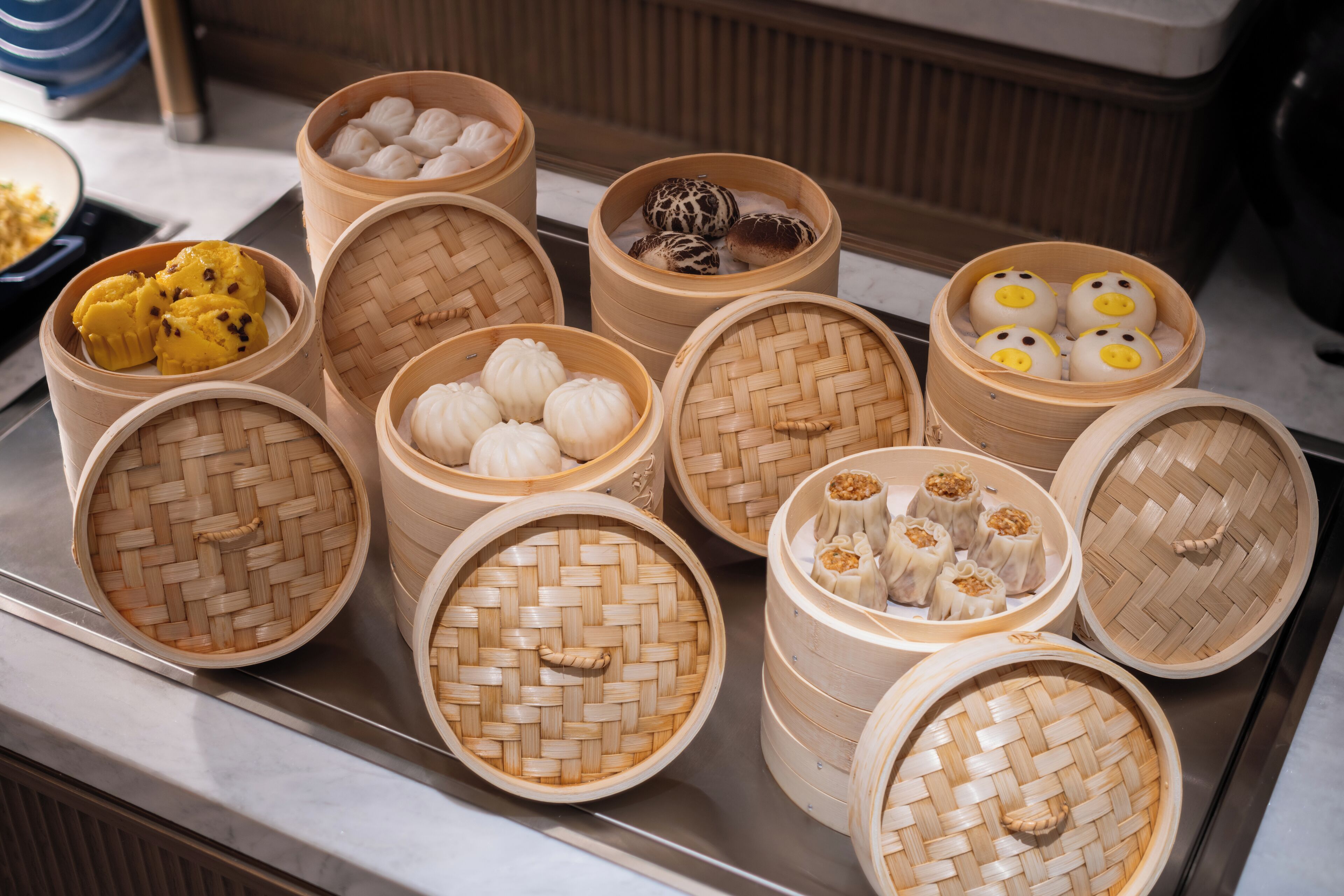 A variety of dim sum dishes in woven bamboo baskets.