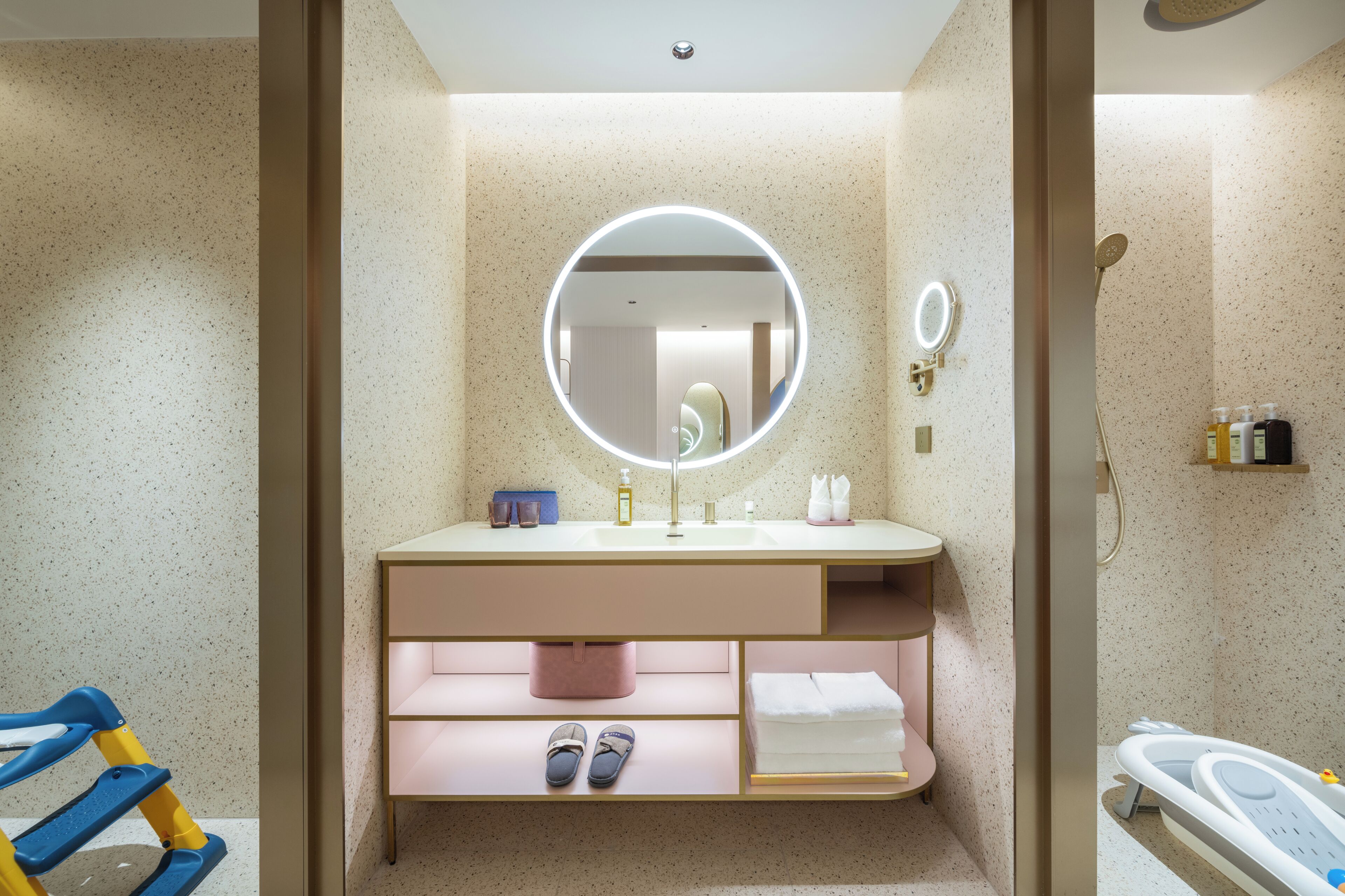 A modern bathroom with a round mirror, a sink, and a shower area.