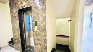 An elevator with a marble wall design, a digital display showing the number 2, and a handrail.