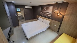 A modern hotel room with a large bed, a bedside table, a mirror, and a wall-mounted air conditioner.