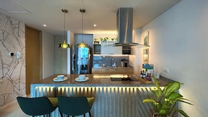 A modern kitchen with a central island, pendant lights, and a stainless steel range hood. - Corozo Berry Loft - Mallorquin View. One block from Buenavista. (Barranquilla)