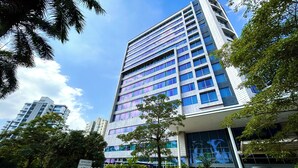 A modern hotel with a glass facade, a visible entrance, and a sign indicating an electronic detection area. - Corozo Berry Loft - Mallorquin View. One block from Buenavista. (Barranquilla)