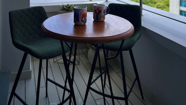 A balcony with two chairs, a small round table, and hanging lights. - Corozo Berry Loft - Mallorquin View. One block from Buenavista. (Barranquilla)