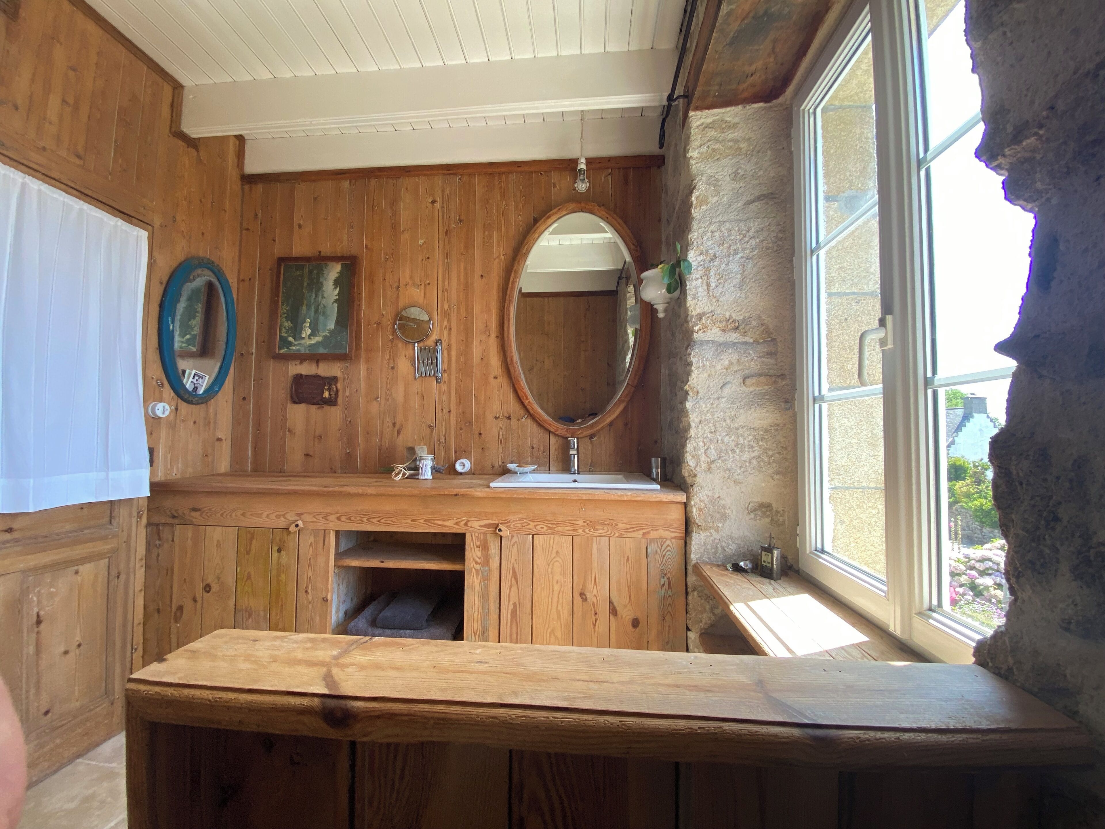 A wooden bathroom with a sink, mirror, and window.