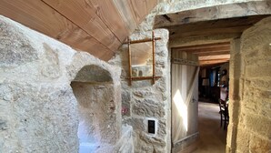 Un intérieur aux murs de pierre, avec un plafond en bois, une porte rustique et une petite fenêtre.