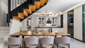 Een moderne keuken met een houten trap, een eettafel gedekt voor zes personen en inbouwapparatuur.