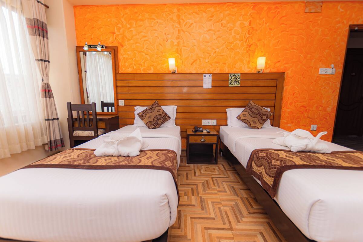 A hotel room with two beds, a wooden headboard, a mirror, a nightstand, and a chair.