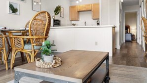 Een moderne keuken met witte kasten, een houten kookeiland en een eethoek met rieten stoelen.