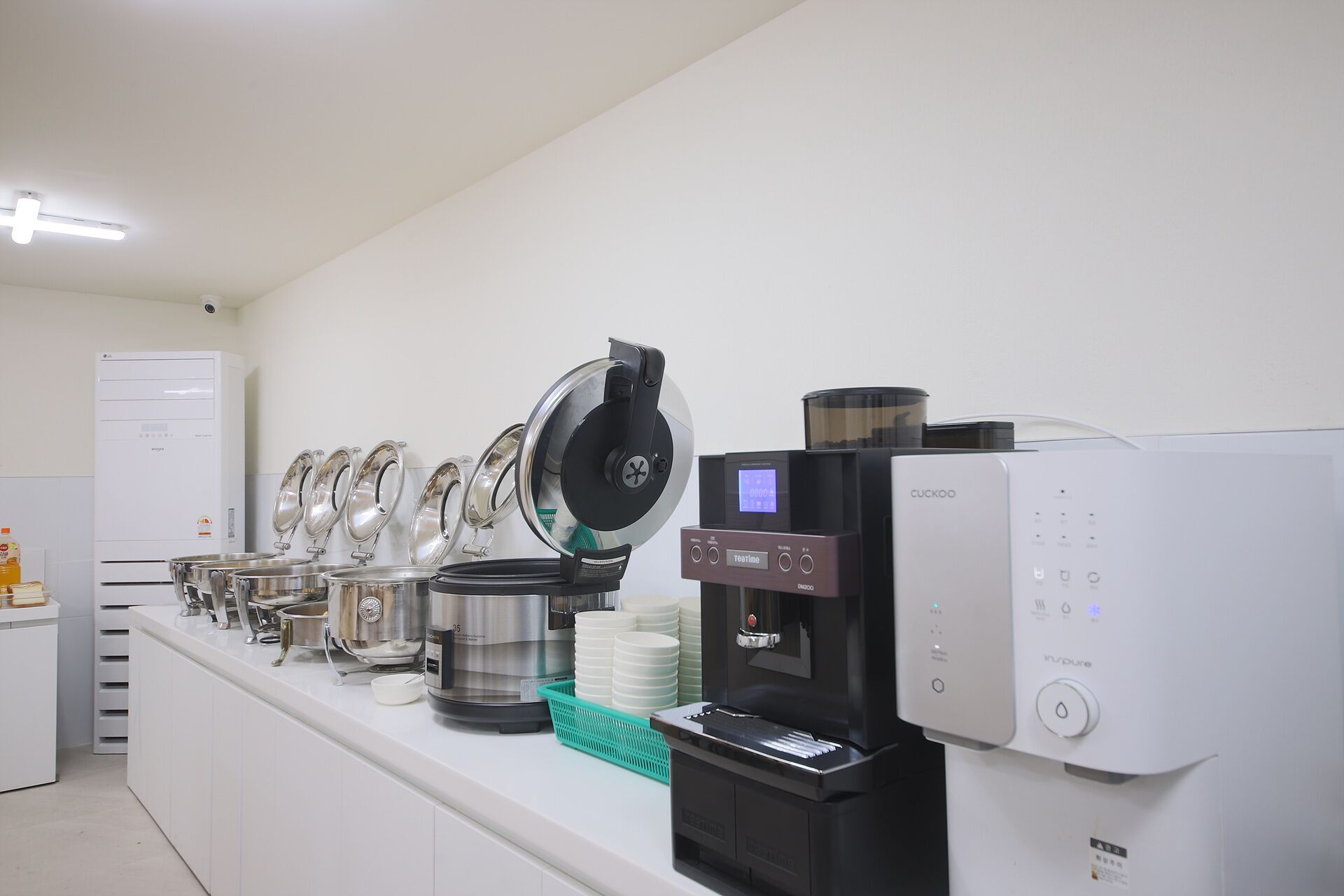 A coffee station with multiple coffee machines and a refrigerator.