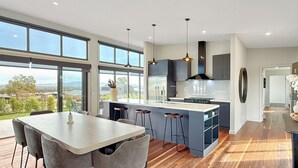 Une cuisine moderne dotée d’un grand îlot central, de tabourets de bar et offrant une vue sur l’extérieur.