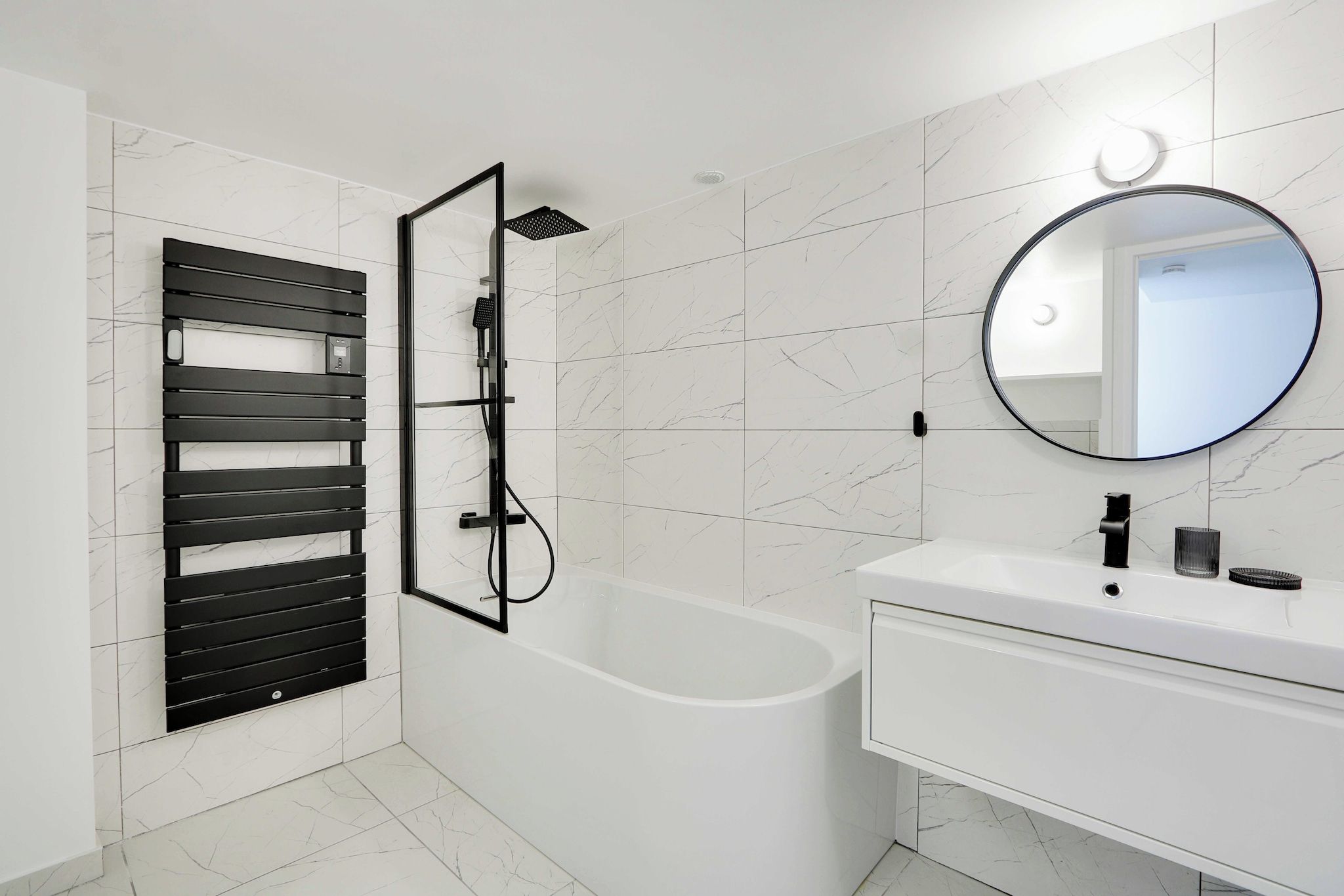 Une salle de bain moderne avec une baignoire, un meuble-lavabo avec un miroir et un panneau noir.