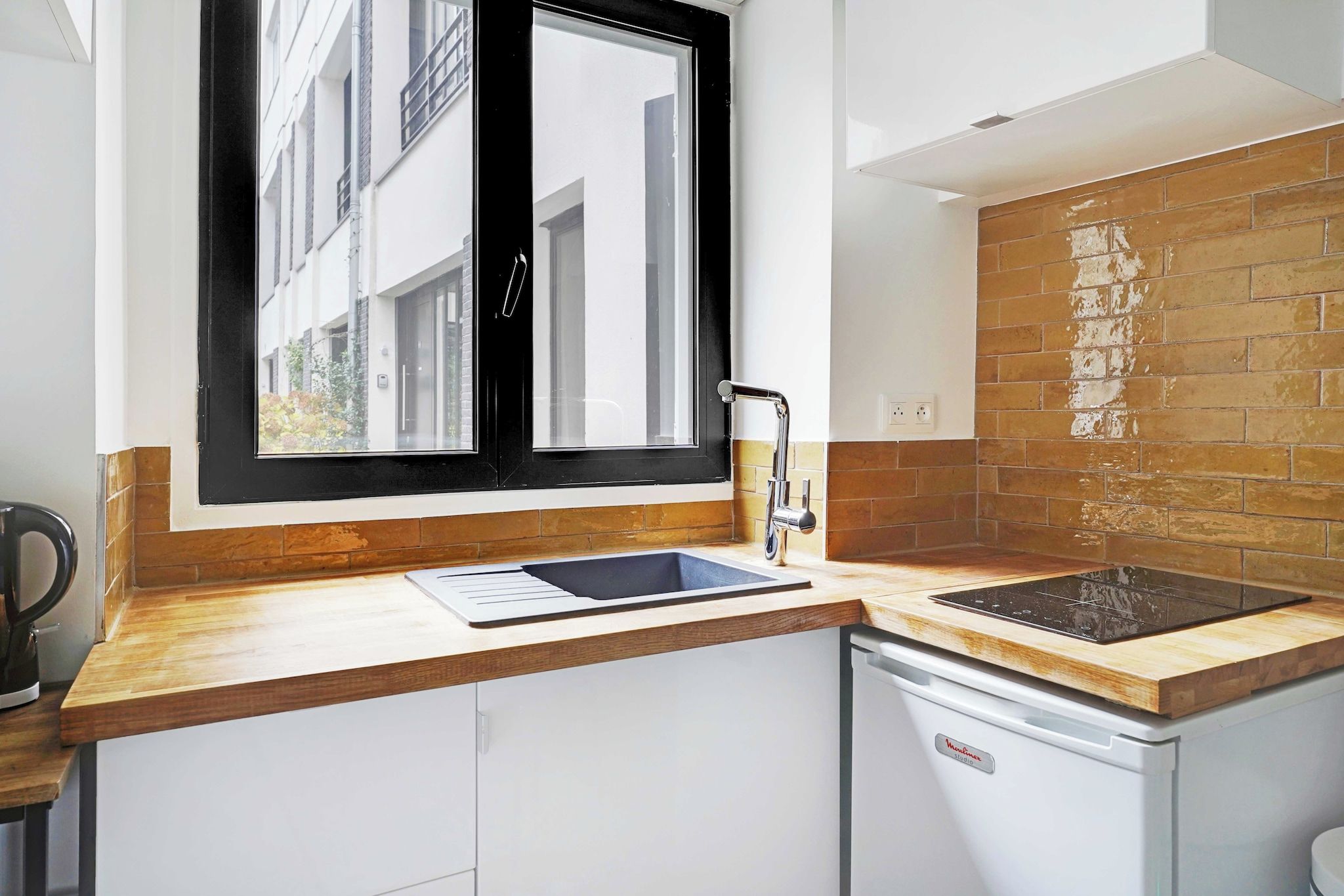 A compact kitchen with a window, a built-in sink, and a compact dishwasher.