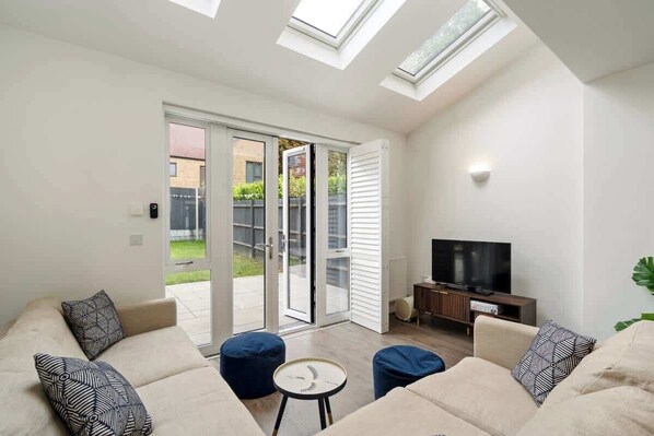 A living room with a sofa set, a coffee table, a television, and a sliding glass door leading to an outdoor area.