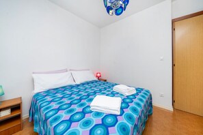 Un dormitorio con cama, mesita de noche, lámpara y armario.