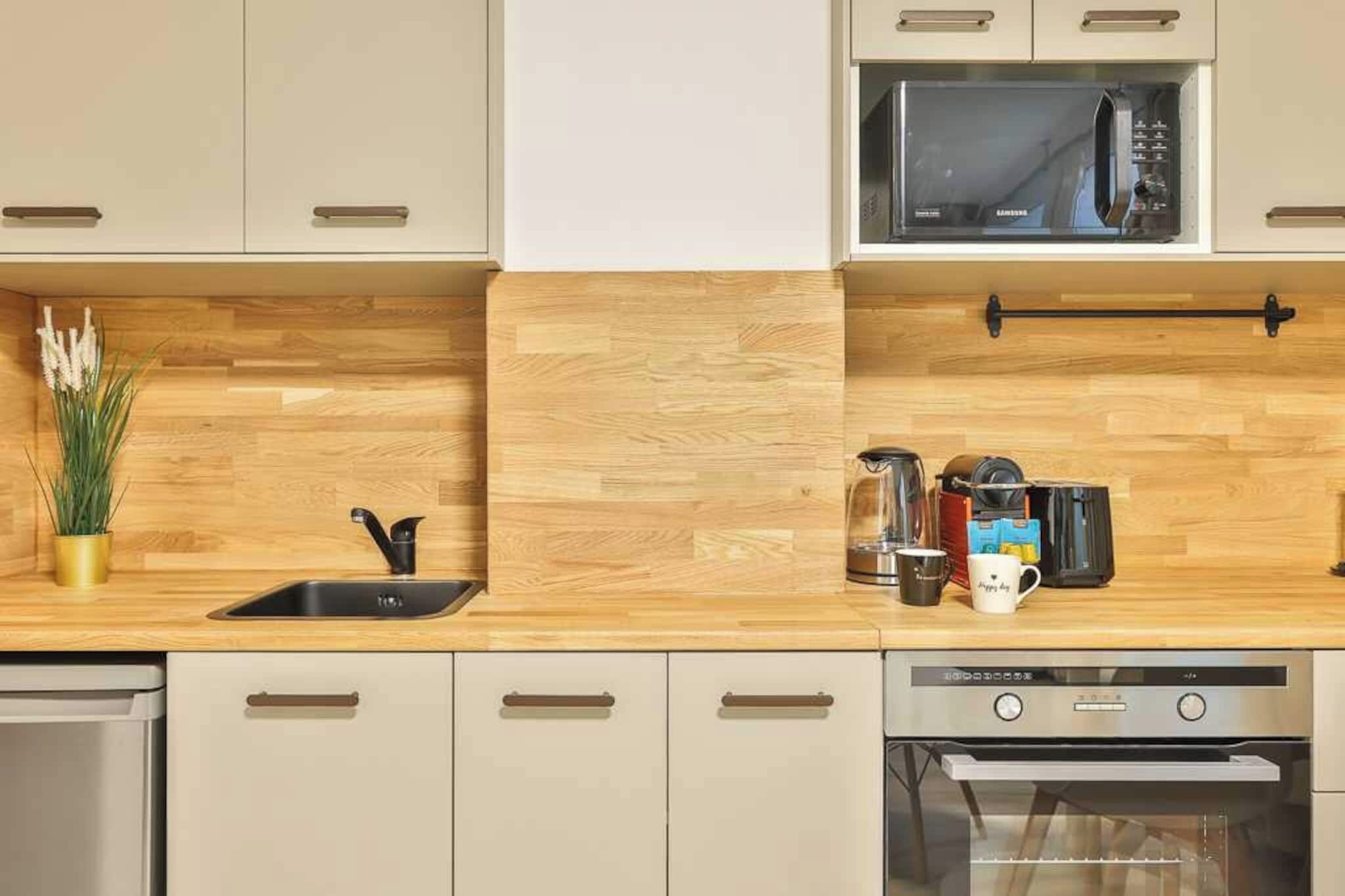 A modern kitchen with wooden cabinetry, a stainless steel sink, a microwave, and a dishwasher.