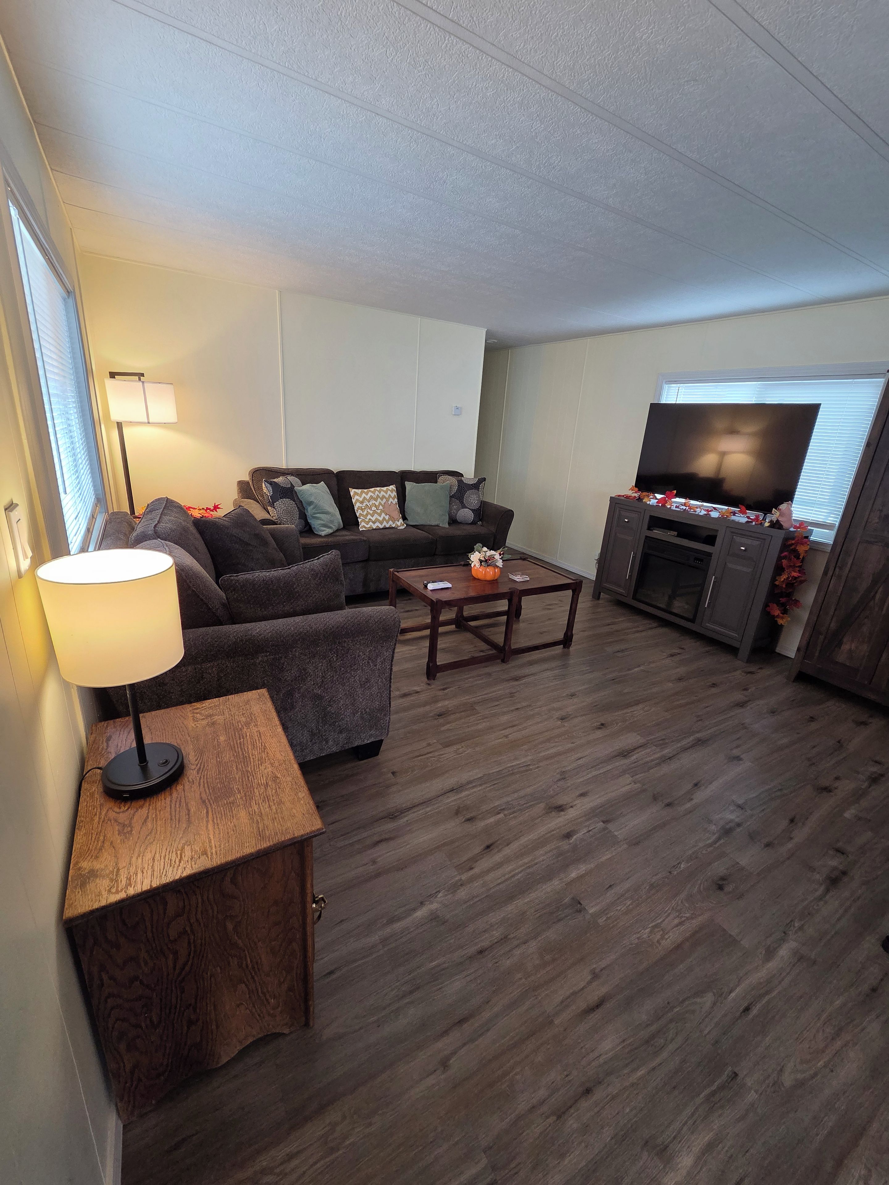 Una sala de estar con un sofá modular, una mesa de centro, un televisor y una lámpara.