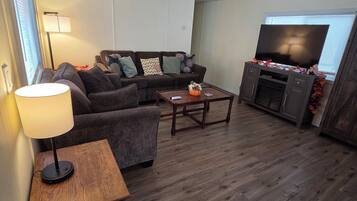 Una sala de estar con un sofá modular, una mesa de centro, un televisor y una lámpara.