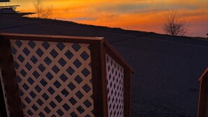 A wooden deck with a lattice railing overlooking a calm body of water during sunset. - Sunset Paradise (Moses Lake)