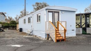 A mobile home with a small porch and a staircase leading to the entrance. - Sunset Paradise (Moses Lake)