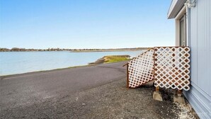 A waterfront property with a paved driveway leading to a building, a wooden fence, and a clear view of the lake. - Sunset Paradise (Moses Lake)