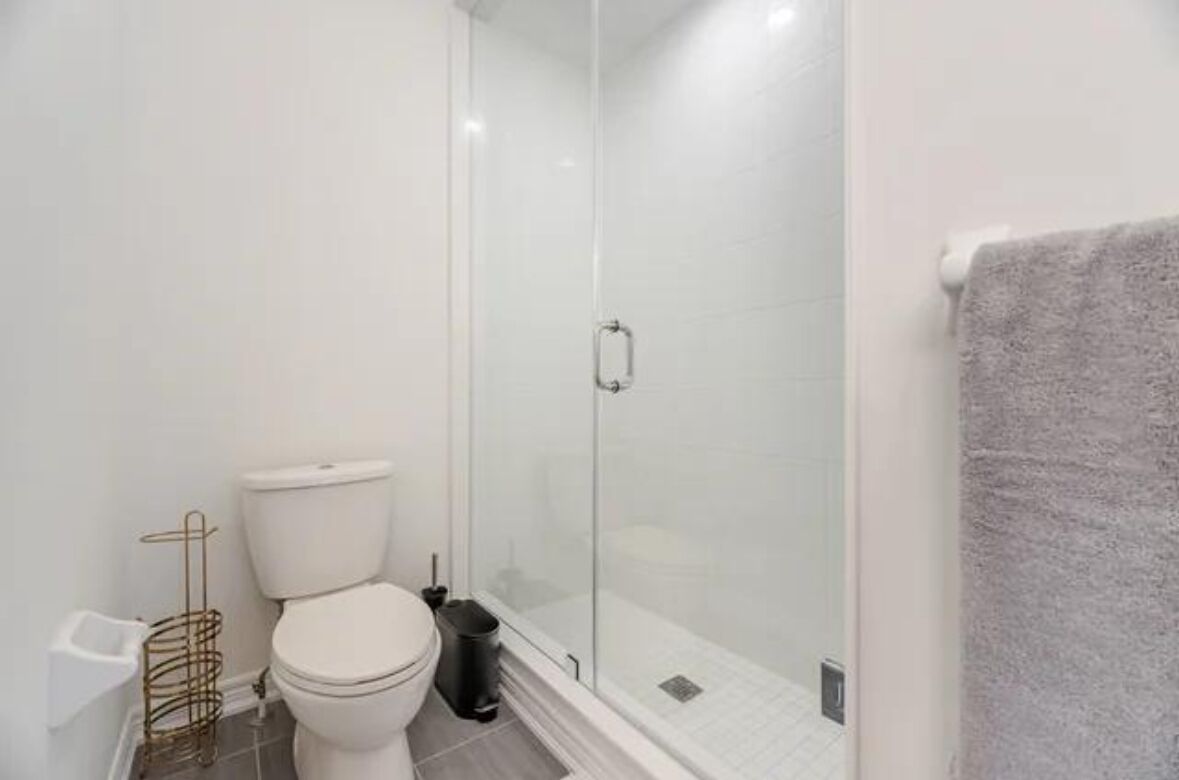 Une salle de bain équipée de toilettes, d’une douche à parois de verre et d’un porte-serviettes.