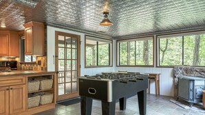 A spacious room with a foosball table, wooden cabinets, and a stone fireplace. - Foxtail Lake Front Chalet with HOT TUB (Innsbrook)