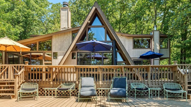 A wooden deck with outdoor seating and umbrellas. - Foxtail Lake Front Chalet with HOT TUB (Innsbrook)