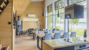 Une cuisine moderne dotée d’un grand îlot central, de murs en bois et de grandes fenêtres offrant une vue sur l’extérieur.