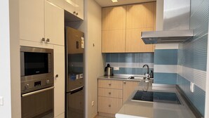 A modern kitchen with stainless steel appliances, wooden cabinets, and a blue backsplash.
