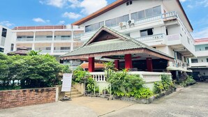 A multi-story building with a traditional roof, a sign indicating 'Top North Guest House', and a well-maintained garden area. - Value Twin Stay | Cozy & Convenient Retreat (Chiang Mai)