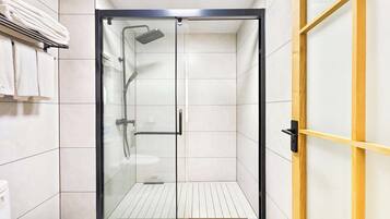 Une salle de bain moderne avec une douche à parois de verre, des carreaux blancs et un cadre de porte en bois.