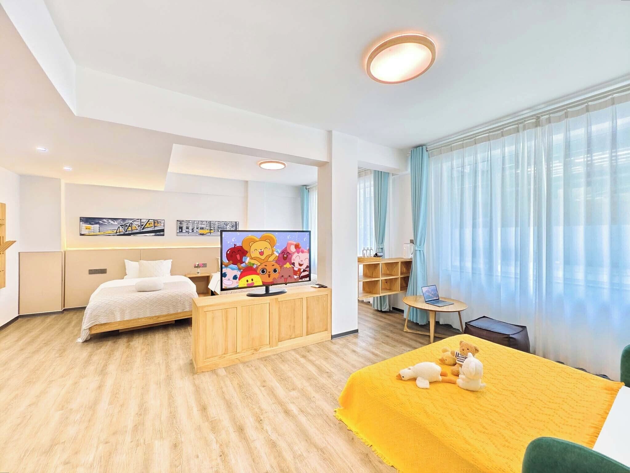 A modern hotel room with a bed, a TV, a desk, and a window with curtains.