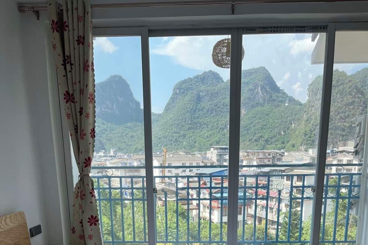 A bedroom with a large bed, a view of mountains, and a balcony with a railing.