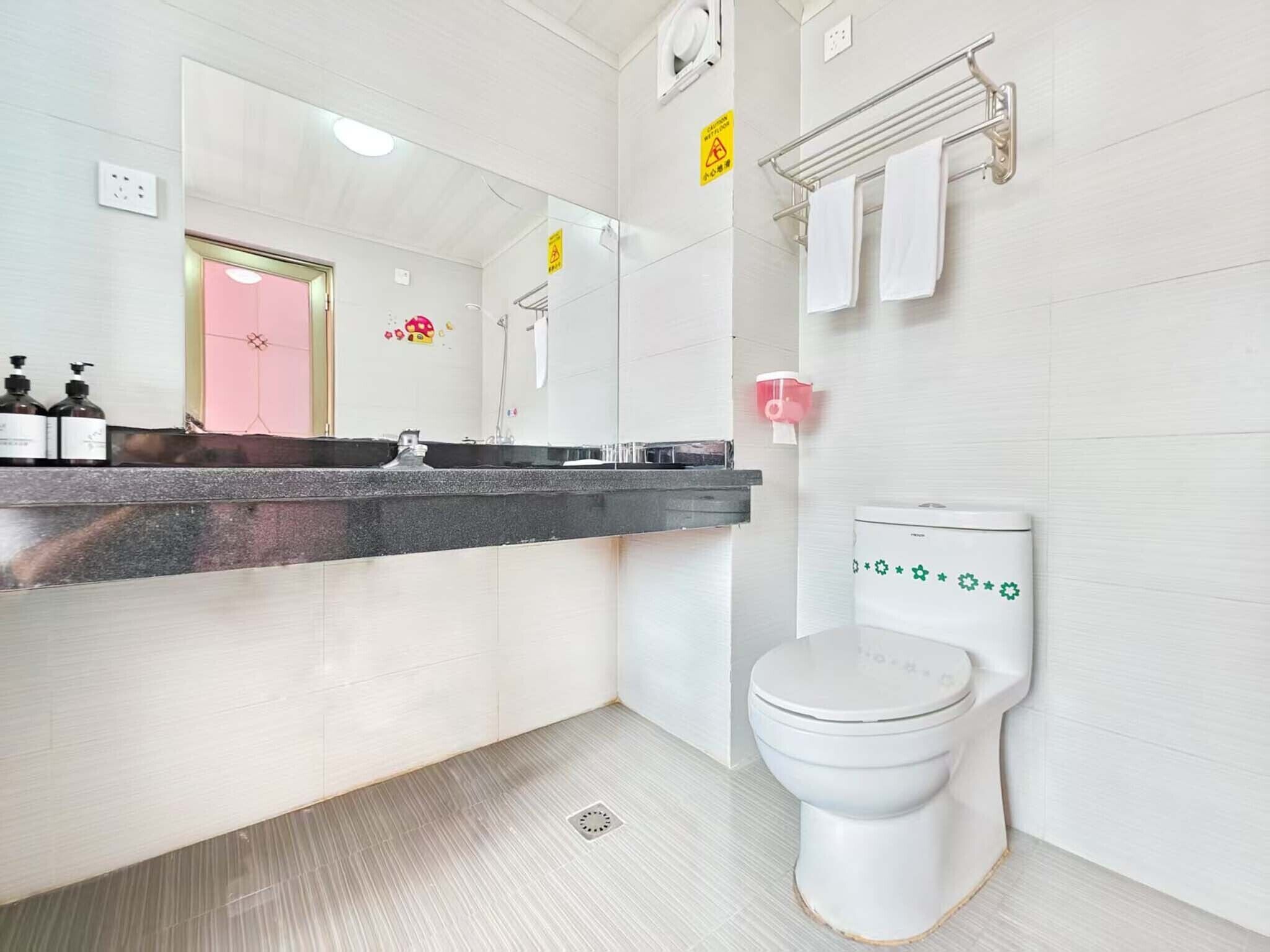 Un baño moderno con inodoro blanco, un lavabo con encimera negra y un espejo sobre el lavabo.
