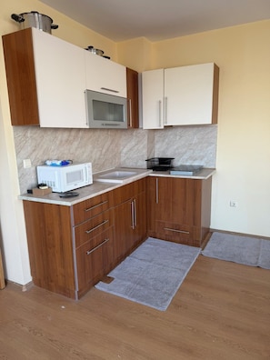 A compact kitchen with a microwave, stove, and cabinets.