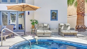 Un espace piscine aménagé avec des chaises longues, un parasol et une plante en pot.