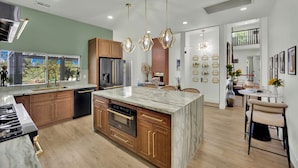 Une cuisine moderne avec des meubles en bois, un îlot en marbre et des luminaires suspendus.