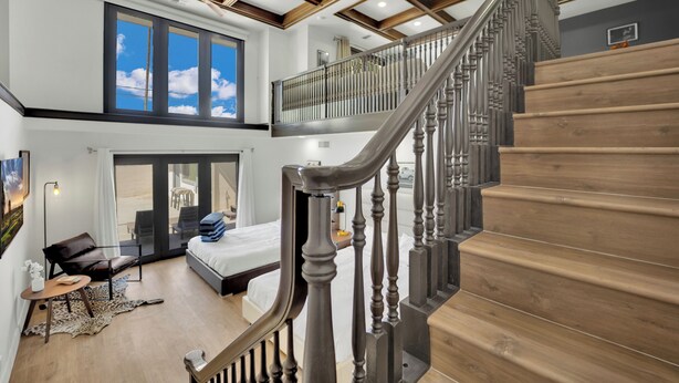 Une pièce spacieuse comprenant un grand lit, un coin salon et un escalier menant à un niveau supérieur.