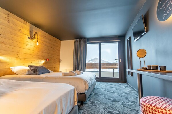 A hotel room with two beds, a wooden headboard, a large window with a view of mountains, a flat-screen TV, and a small table with cups. - Delightful apartment in Saint Chaffrey (SAINT CHAFFREY)