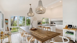 A modern kitchen with white cabinetry, a wooden island, and pendant lighting.