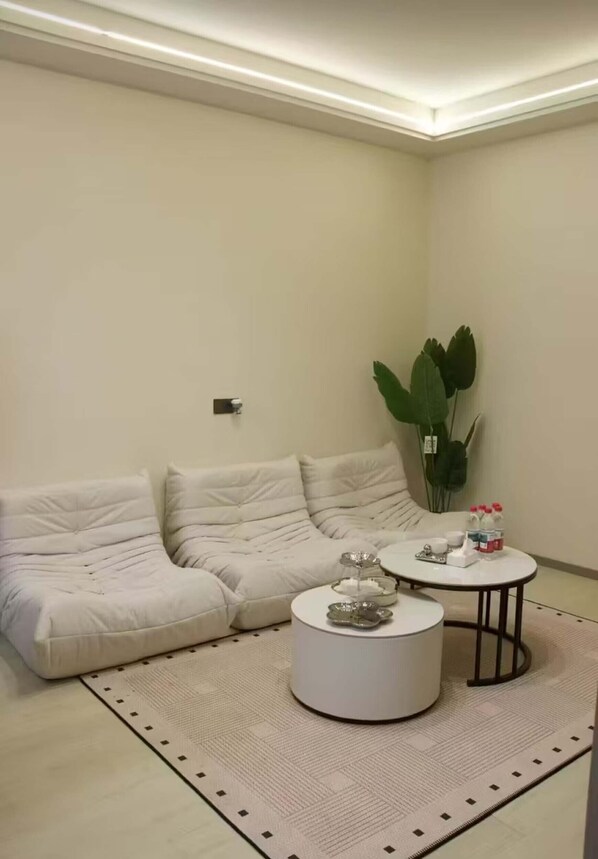 Una sala de estar moderna con un sofá seccional blanco, una mesa de centro redonda y una planta en maceta.