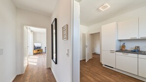 A modern kitchen with white cabinets and a wooden floor.