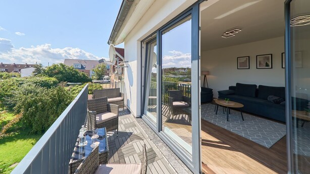 A modern apartment with a balcony, a living area with a sofa and coffee table, and a view of the neighborhood.
