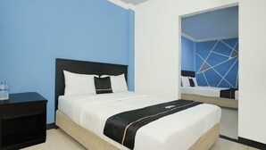 Una habitación de hotel con una cama, una mesita de noche y un espejo.